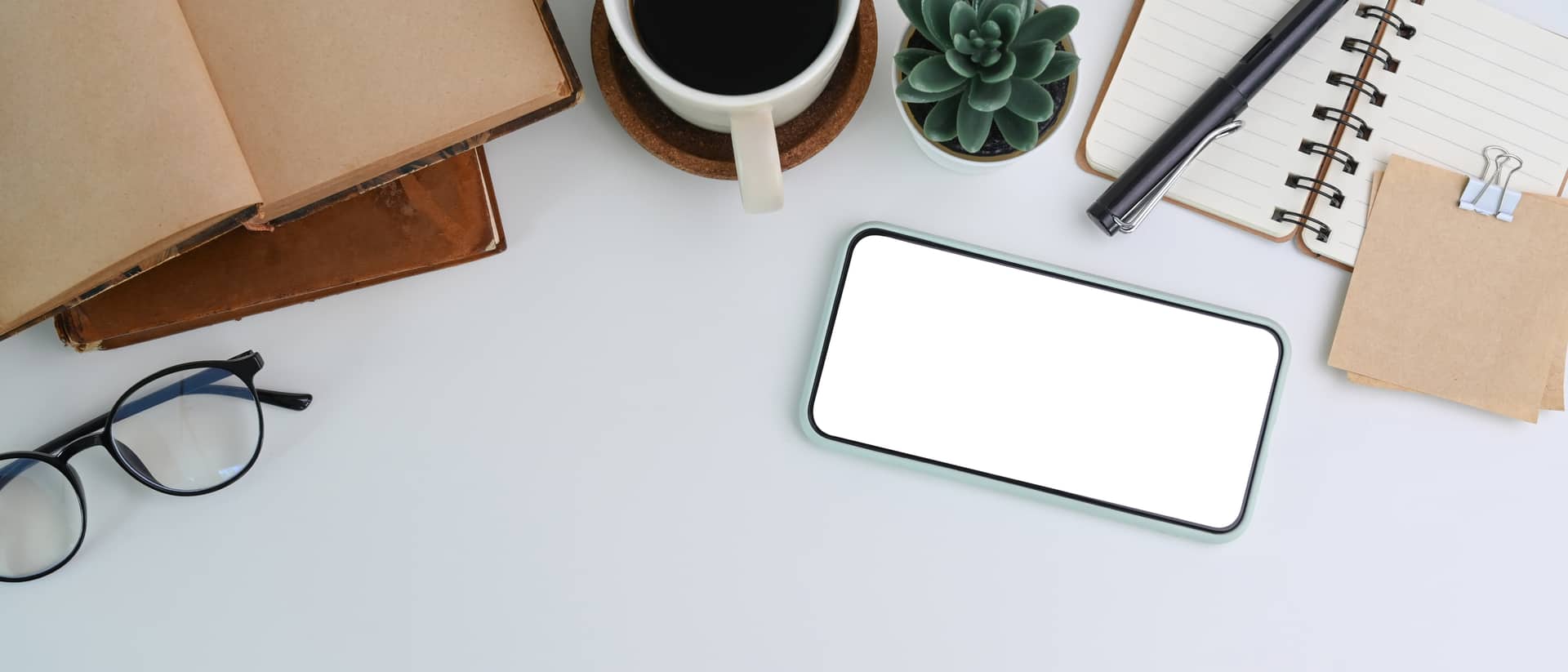 Bureau vu de dessus : carnet, lunettes, téléphone et tasse de café