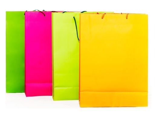 Quatre sacs de boutique colorés alignés sur fond blanc