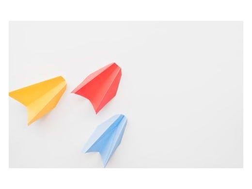 Trois avions en papier colorés sur fond blanc