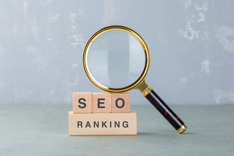Wooden blocks spelling SEO next to a magnifying glass on a desk
